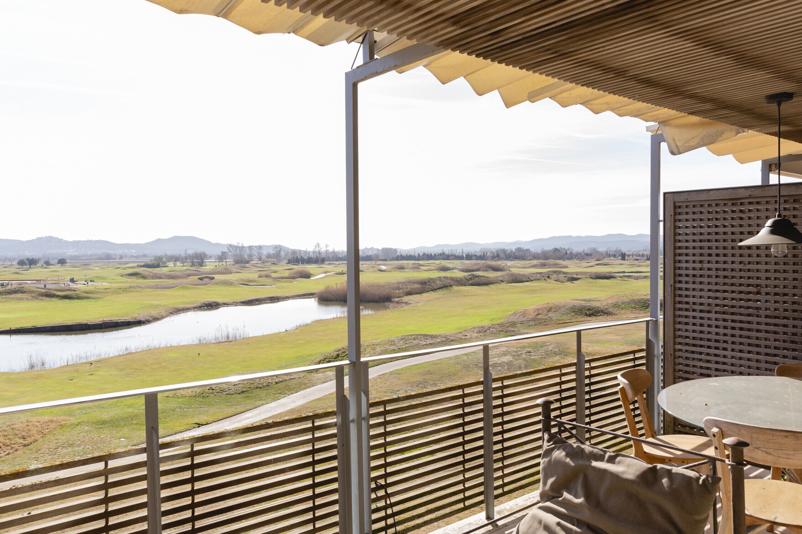 Eine Terrasse mit Blick auf einen Fluss, einem Tisch und Stühlen.