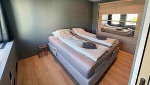 Een moderne slaapkamer met een enkel bed, een klein nachtkastje en een spiegel.
