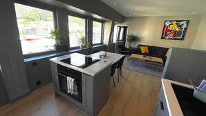 Een moderne keuken met een kookeiland, grote ramen en een zithoek met een bank.