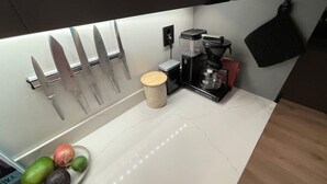 Een keuken met een wit aanrecht, een koffiezetapparaat en een messenhouder.