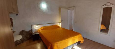 A bedroom with a bed, wooden ceiling, and a window.