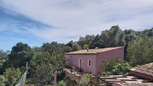 A pink building with a tiled roof, surrounded by greenery and trees. - Bela Vista House - Quinta Amoreira (Loulé)