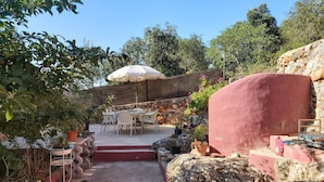 A patio area with outdoor seating, a stone wall, and a large umbrella. - Bela Vista House - Quinta Amoreira (Loulé)