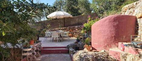 A patio area with outdoor seating, a stone wall, and a large umbrella.
