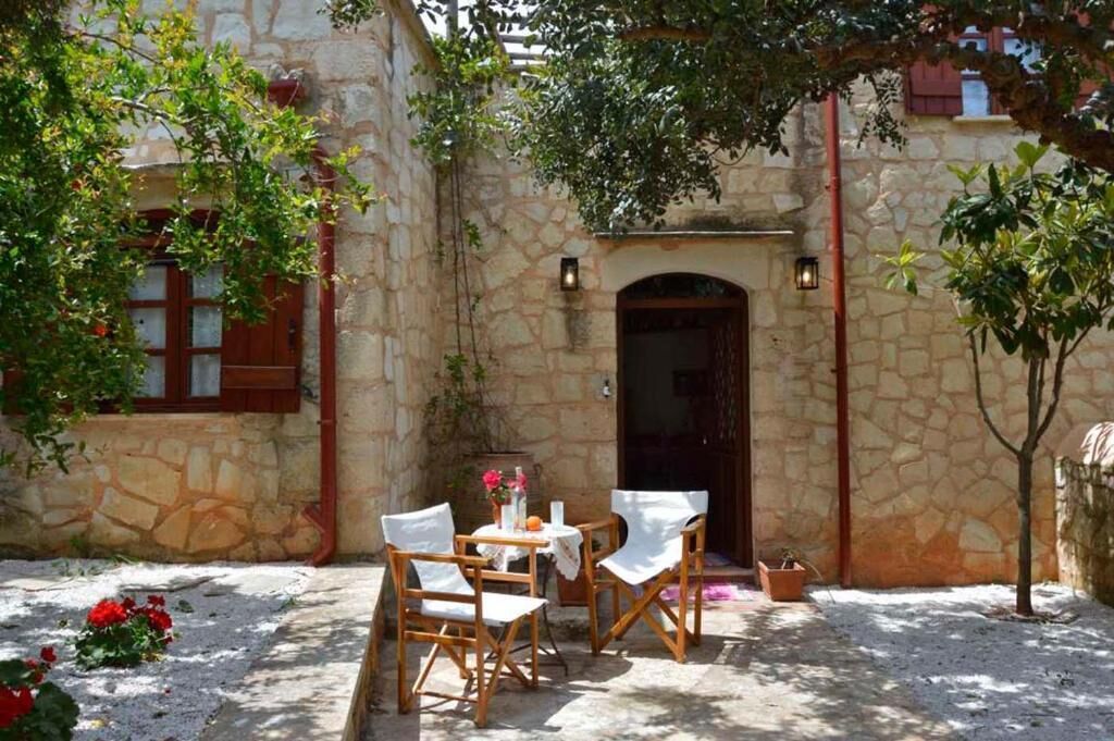 A stone building with a wooden door and a small table with chairs in front.