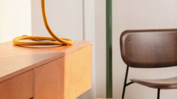 A wooden desk with a yellow lamp, a mustard-colored chair, and a green accent wall.