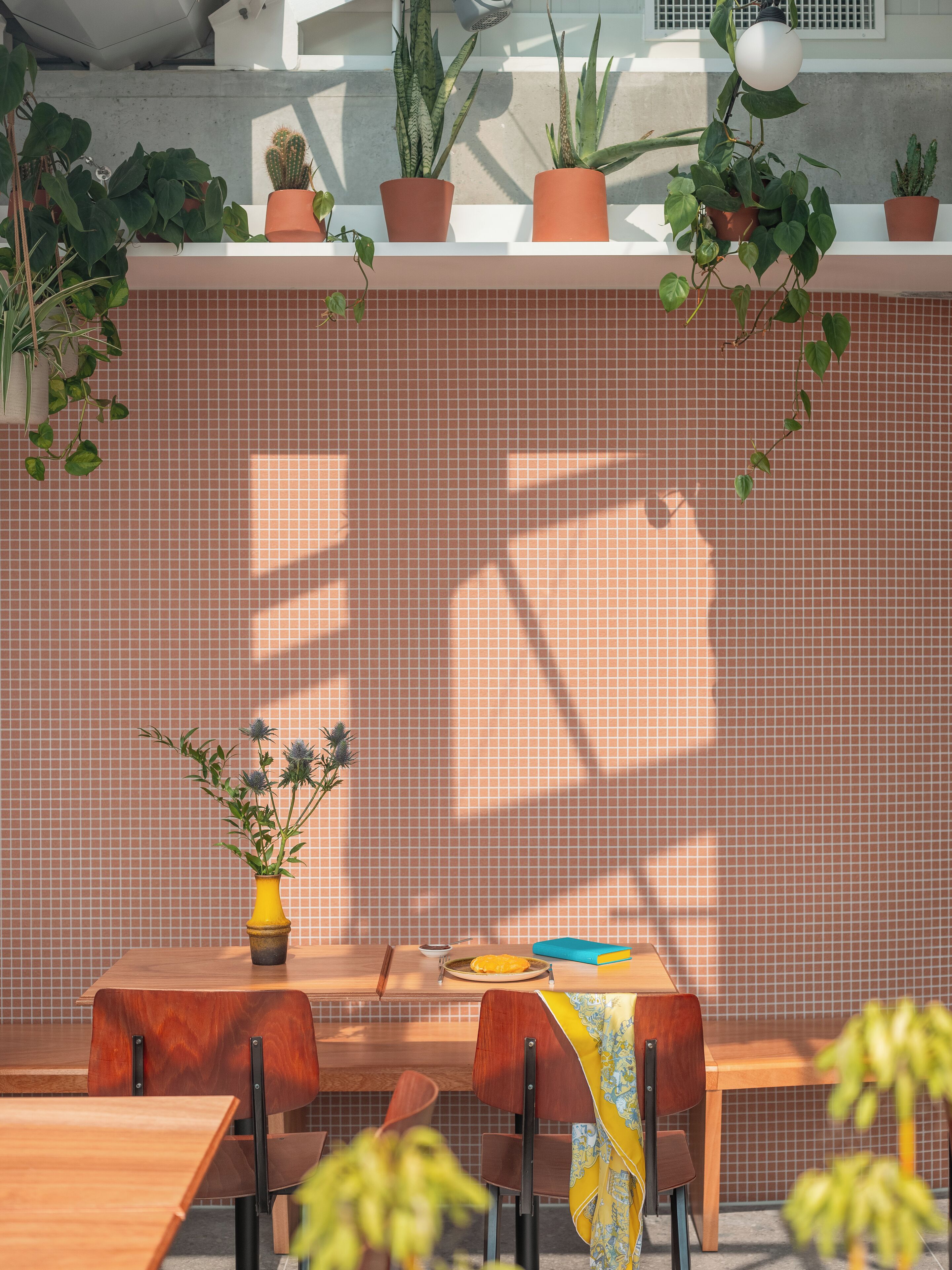 A dining area with a tiled wall, potted plants, and a table with chairs.