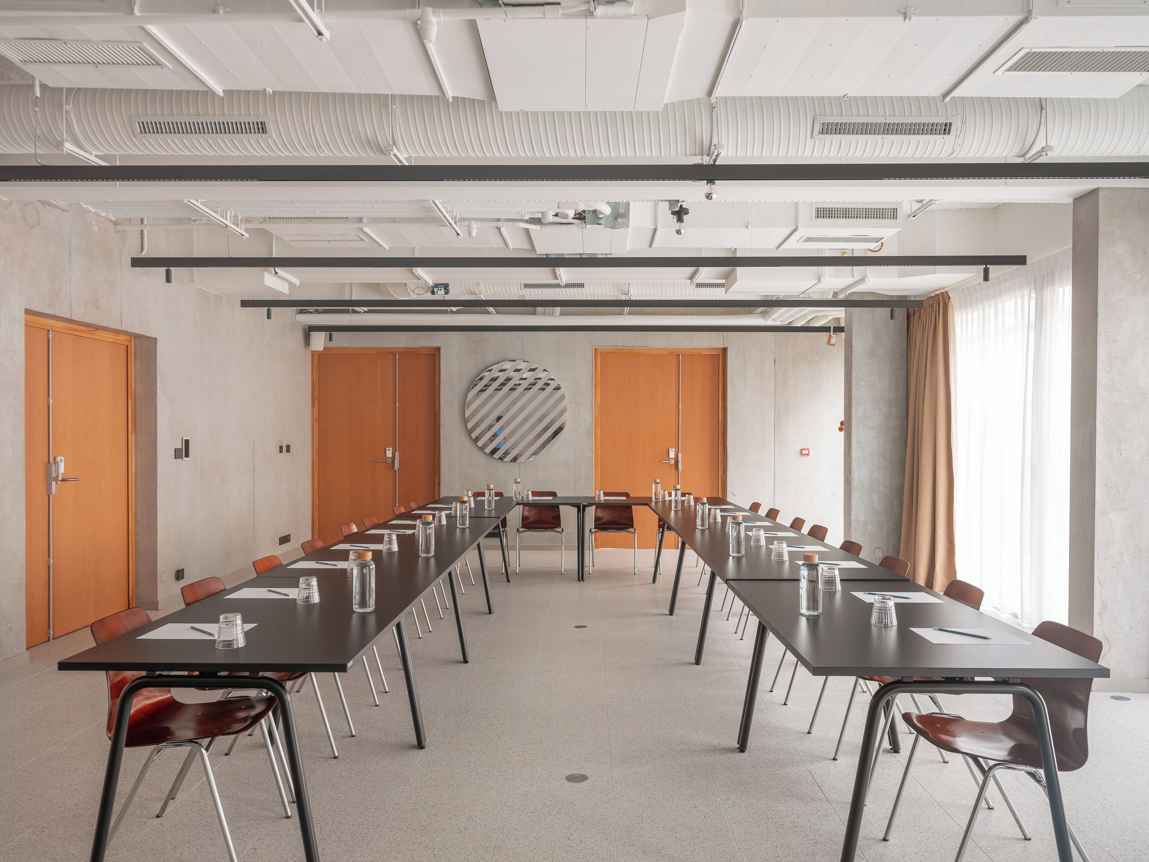 A conference room with a long table, chairs, and a round mirror on the wall.