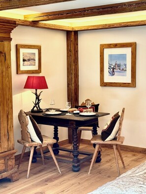 Un coin repas avec une table en bois, des chaises, des tableaux encadrés au mur et une lampe rouge.