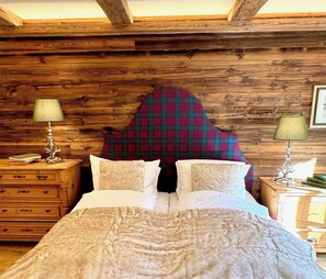 Une chambre à coucher aux murs lambrissés, avec un lit, deux tables de chevet et une tête de lit à carreaux.