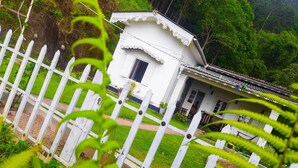 A white house with a porch, surrounded by a white picket fence and lush greenery. - Hill House Haldummulla (Haldummulla)