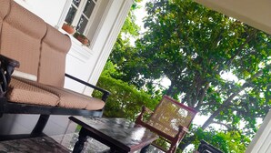 A covered outdoor seating area with a marble floor, a sofa, a table, and a chair. - Hill House Haldummulla (Haldummulla)