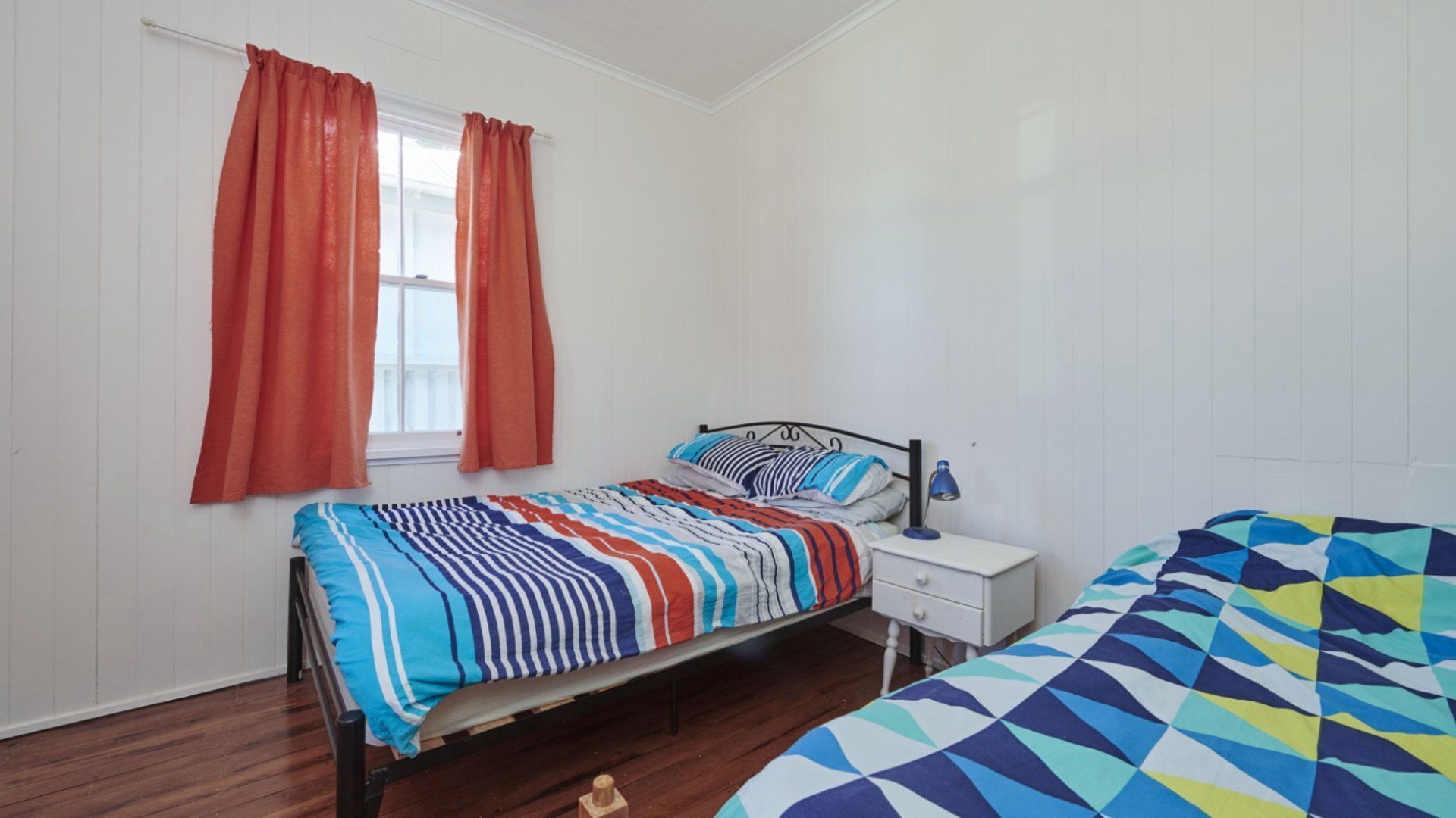 A bedroom with a bed, a nightstand, a lamp, and a window with curtains.