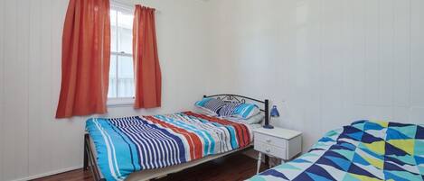 A bedroom with a bed, a nightstand, a lamp, and a window with curtains.