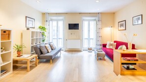 A spacious living room with a grey sofa, a red sofa, a wooden coffee table, and a bookshelf. - Hiro Studio - Spanish Steps (Roma)