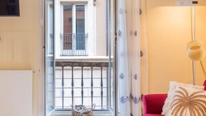 A living room with a red sofa, a small table, a floor lamp, and a view of a balcony with a railing. - Hiro Studio - Spanish Steps (Roma)