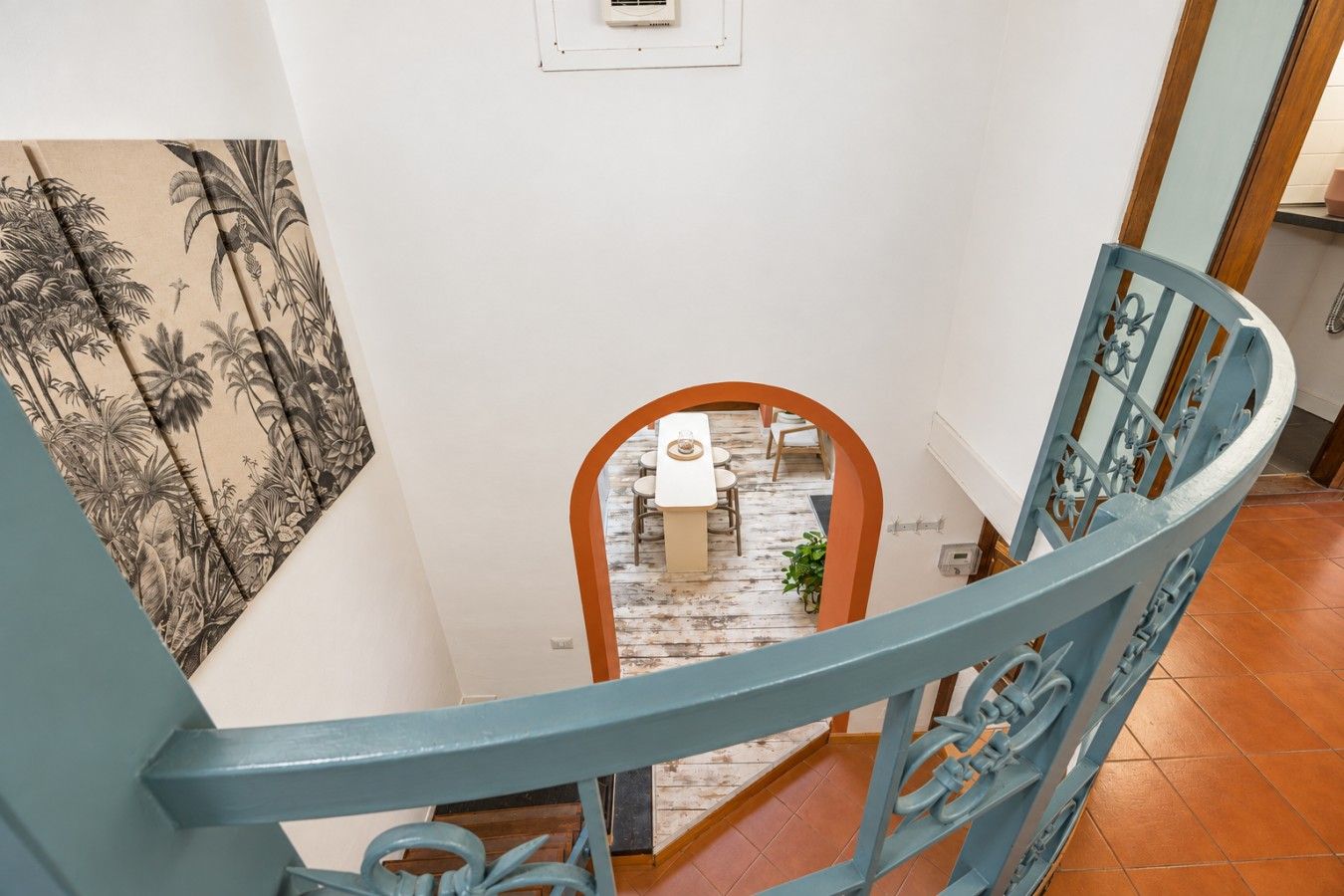 A staircase with a blue railing leading to a dining area with a table and chairs.
