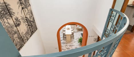 A staircase with a blue railing leading to a dining area with a table and chairs.