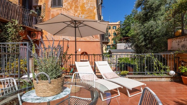 Un espace extérieur ensoleillé, aménagé avec deux fauteuils confortables, une table et un grand parasol.