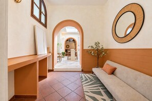 A hallway with a sofa, a mirror, and an arched doorway leading to a dining area.