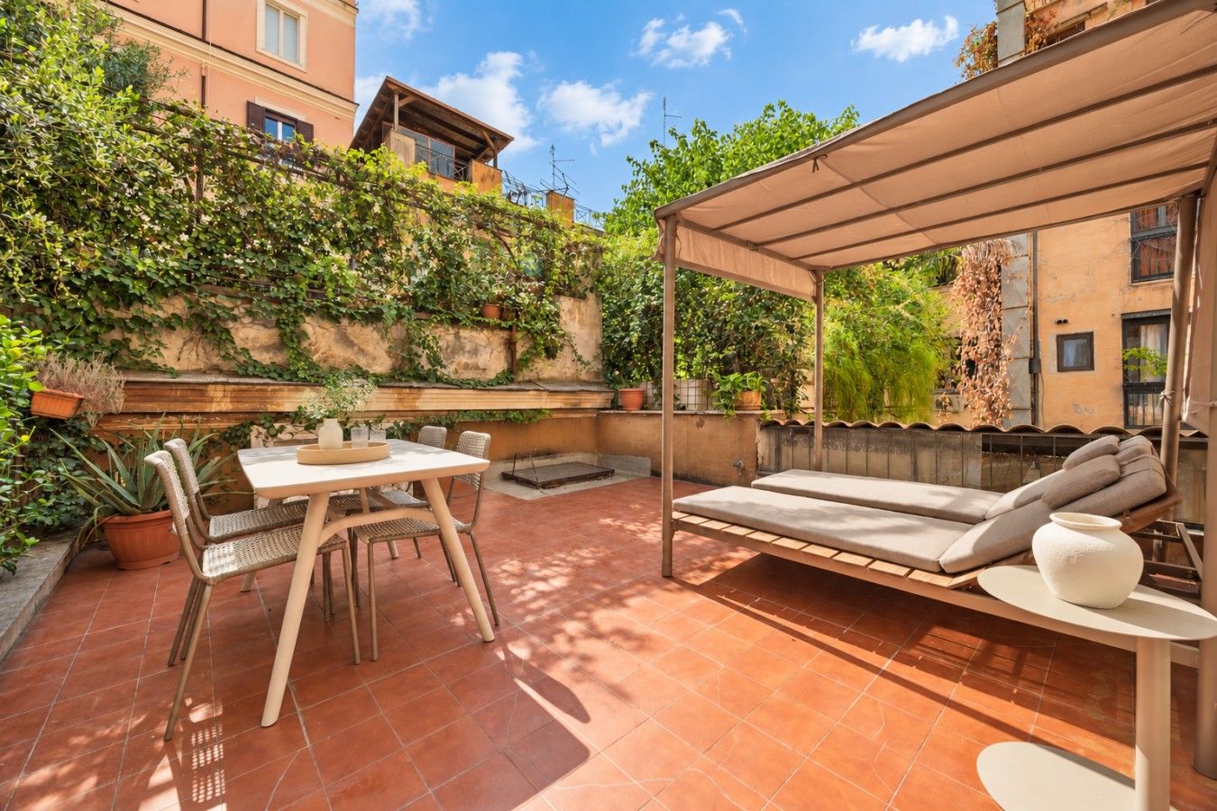 A patio with a table and chairs, a cushioned seating area, and a pergola.