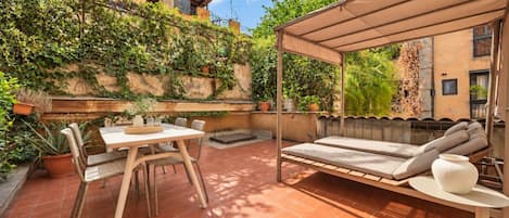 A patio with a table and chairs, a cushioned seating area, and a pergola.