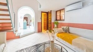 Un salon moderne avec un escalier, un canapé agrémenté d’un plaid jaune et un vase décoratif.