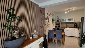 A modern kitchen with white cabinets, a wooden countertop, and a dining area with a table and chairs.