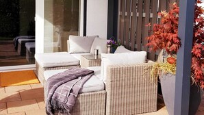 A patio area with wicker furniture, a wooden fence, and a hanging light fixture.