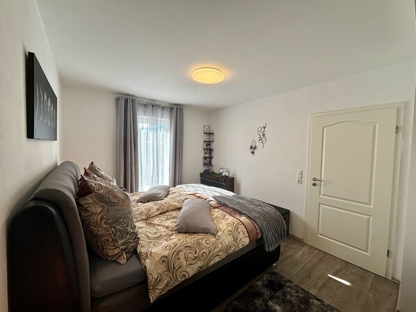 Un dormitorio con cama, sofá, mesita de noche y una puerta.