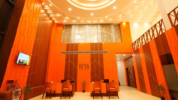 A reception area with a modern design, featuring a central chandelier, a large digital screen, and several seating areas. - IRA By Orchid Noida (Noida)