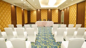 A conference room with white chairs arranged in rows, a table with a checkered tablecloth, and a patterned carpet. - IRA By Orchid Noida (Noida)