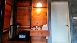 Un intérieur en bois avec une étagère sur laquelle se trouve une radio, une porte et une petite table sur laquelle sont posés divers objets.