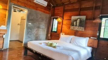 A wooden cabin room with a bed, a shower, and a window.