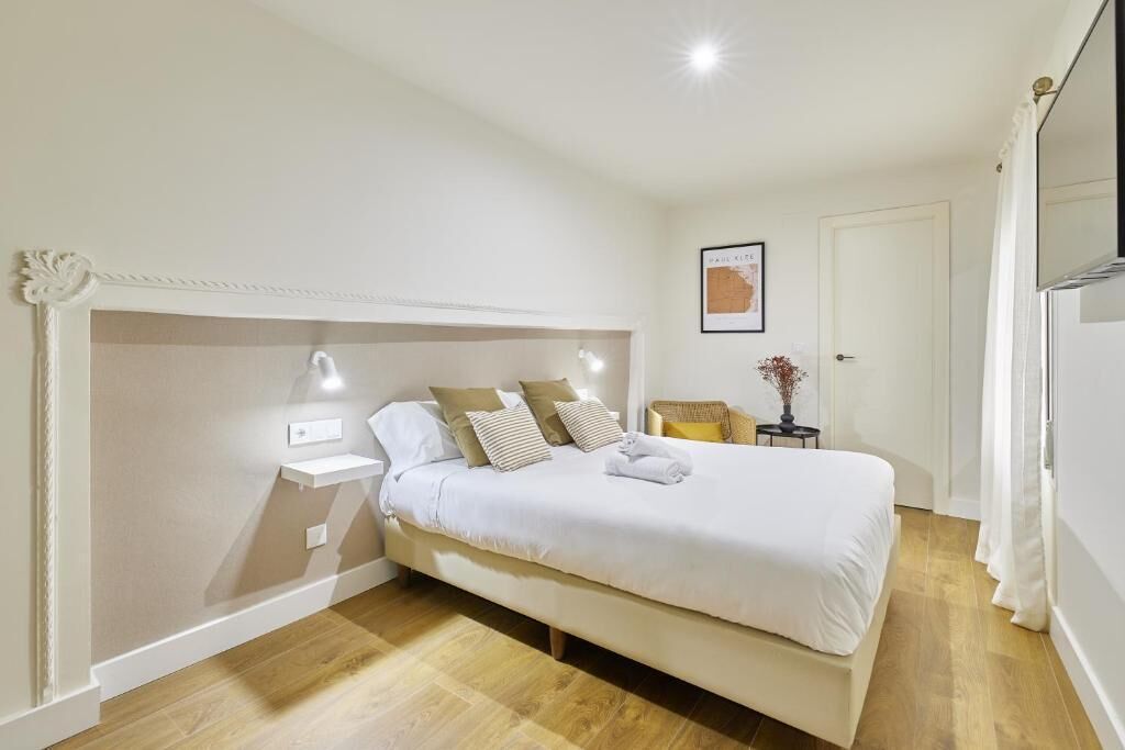 A bedroom with a bed, bedside tables, a nightstand, a framed picture, and a door.