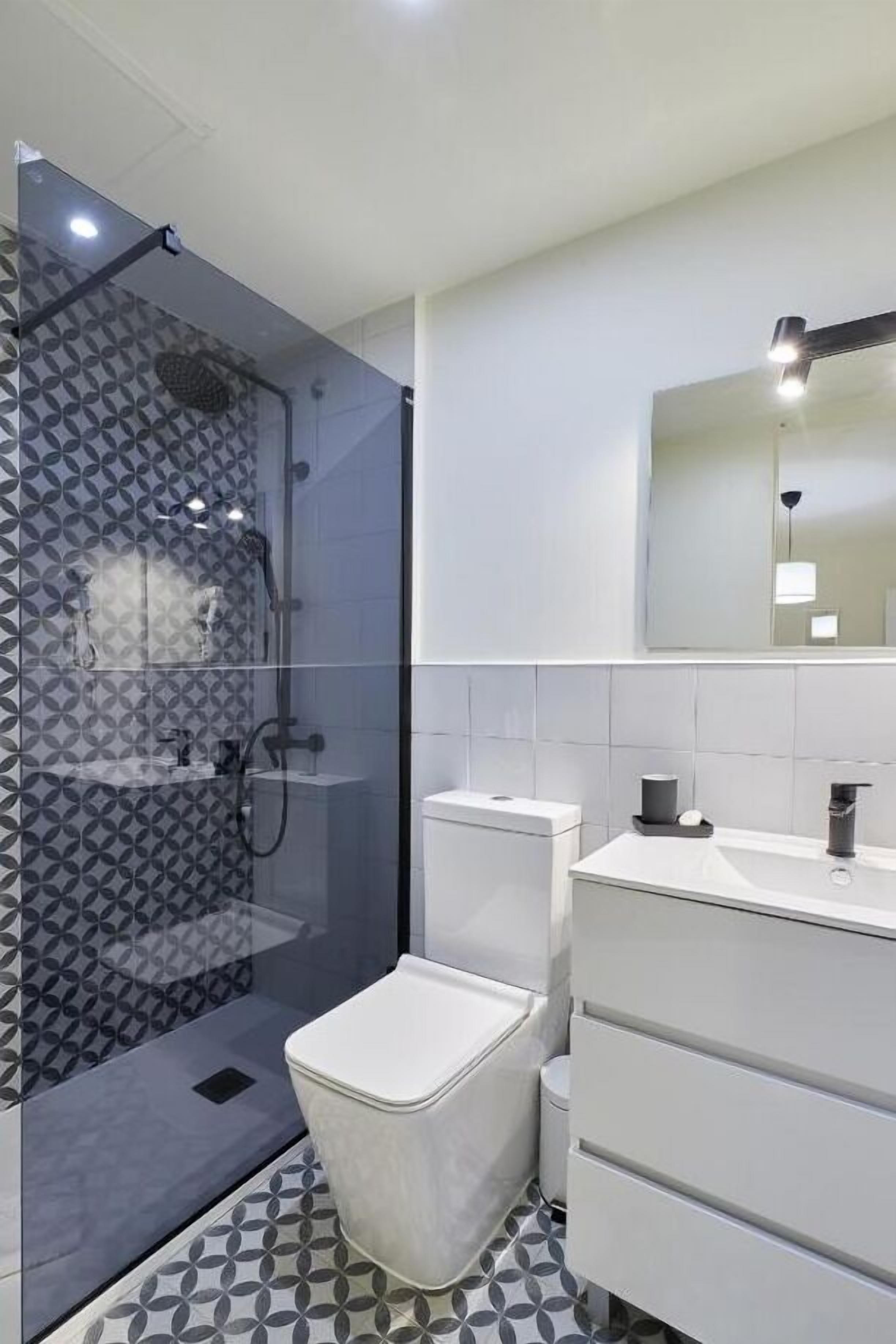 A modern bathroom with a shower, toilet, and vanity.
