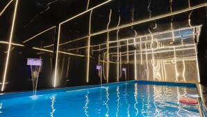 Piscina interior com padrões de luz geométricos nas paredes e no teto.