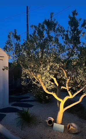 Surrounded by a well-manicured tree and a gravel path, this serene outdoor space offers a peaceful retreat.