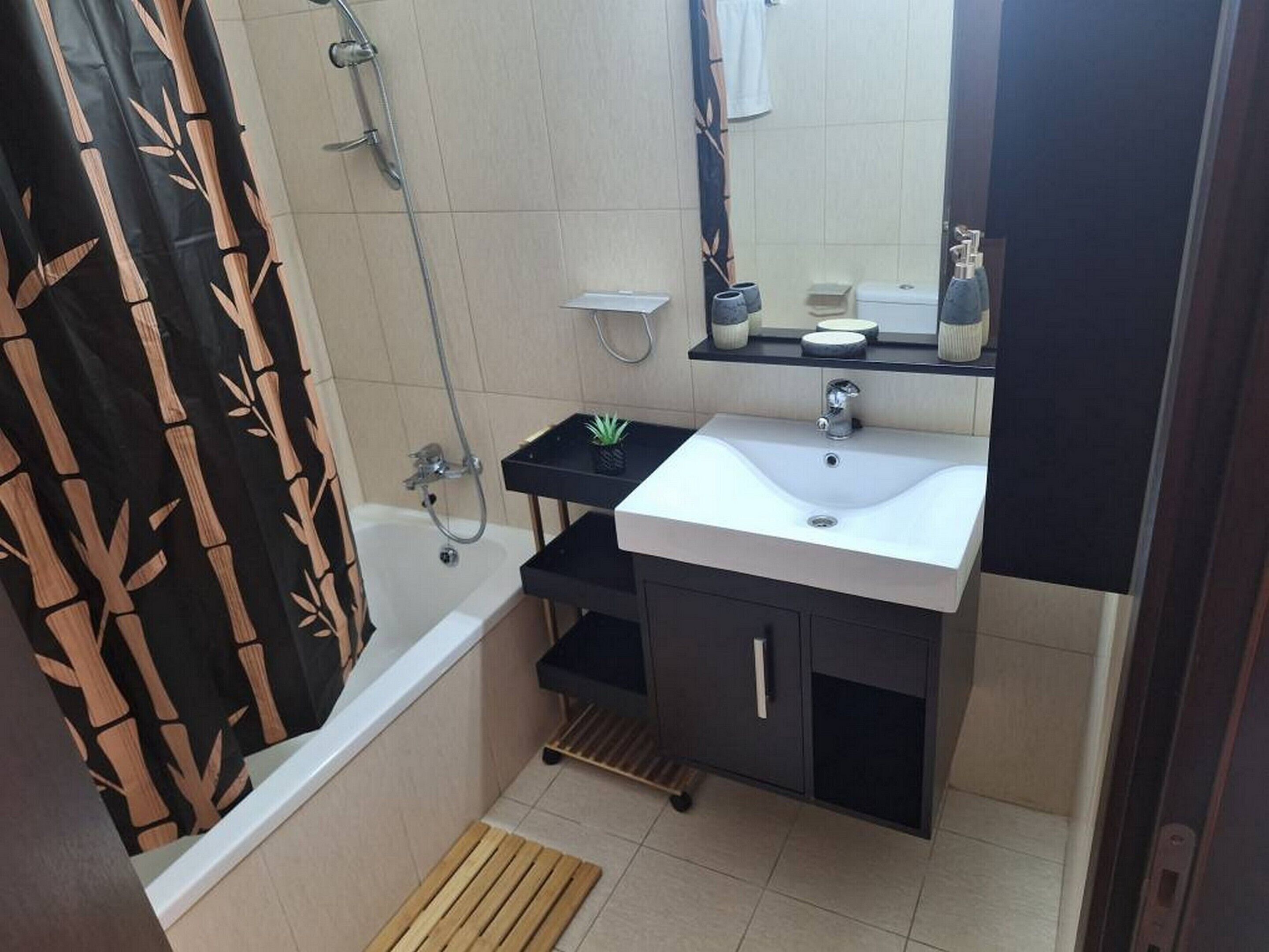 Un baño con bañera, lavamanos, espejo y ducha.
