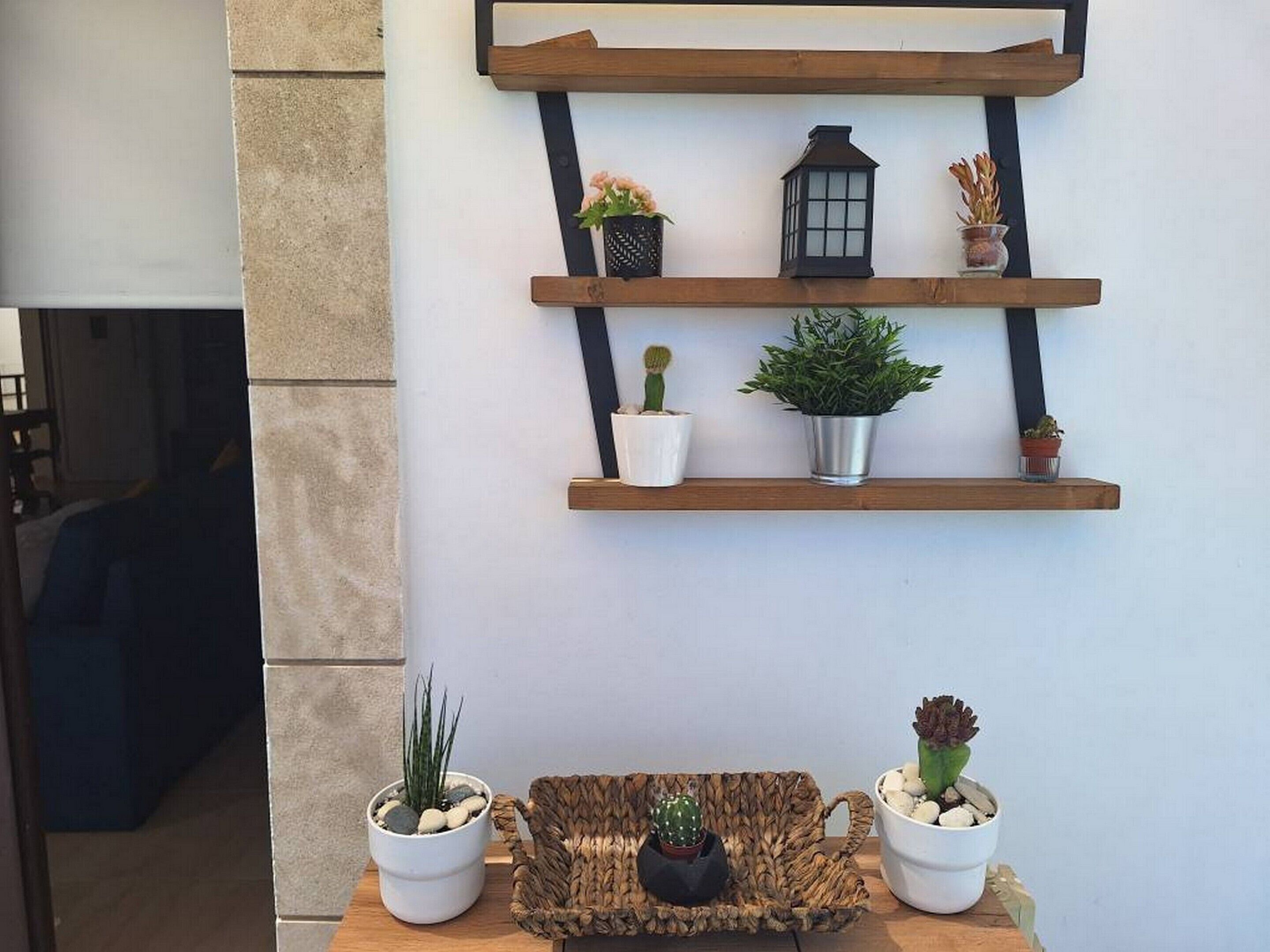 A wall-mounted shelf with potted plants and a lantern.