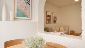 Ein gemütlicher Wohnbereich mit einer Couch, Kissen und einem kleinen Tisch mit einer Vase.