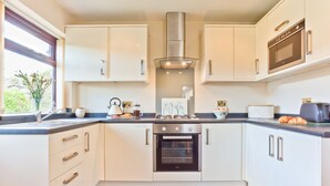 A modern kitchen with white cabinetry, a stainless steel range hood, and a built-in oven. - Lothlorien in Grange-over-sands With Bay Views (Grange-over-Sands)
