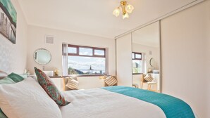 A bedroom with a large bed, a window with a view, a mirror, and a ceiling light. - Lothlorien in Grange-over-sands With Bay Views (Grange-over-Sands)