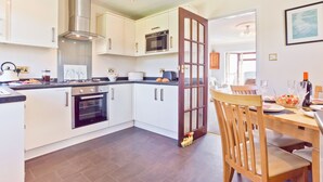 A modern kitchen with white cabinets, a built-in oven, and a microwave. - Lothlorien in Grange-over-sands With Bay Views (Grange-over-Sands)
