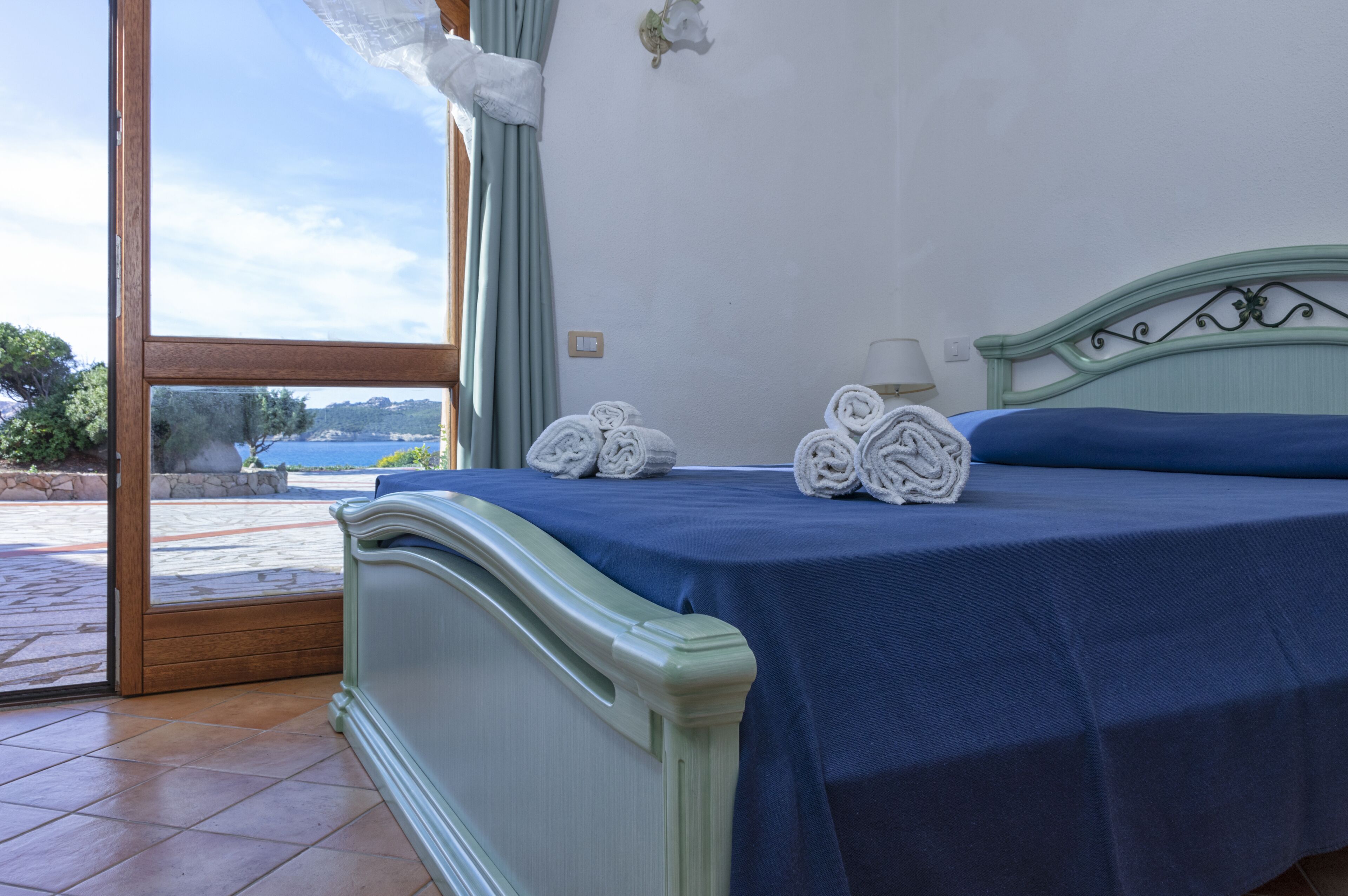 Un dormitorio con cama, vistas al mar y un balcón.