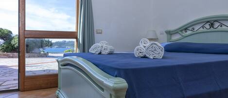 Un dormitorio con cama, vistas al mar y un balcón.