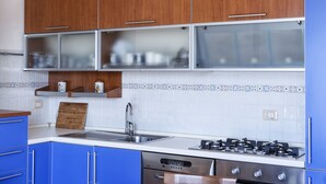 A modern kitchen with blue cabinets, a stainless steel stove, and a tiled backsplash. - Lovely apartment with sea view (Santa Reparata)