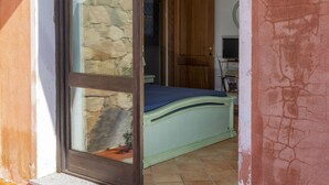 A room with a bed, a wooden door, and a stone wall. - Lovely apartment with sea view (Santa Reparata)