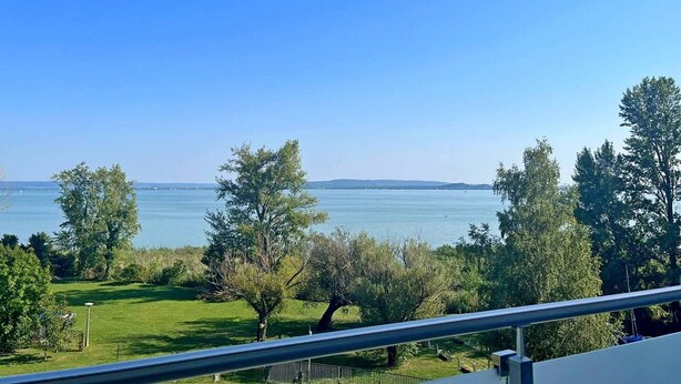 Un balcón con vistas despejadas a un lago y colinas lejanas.