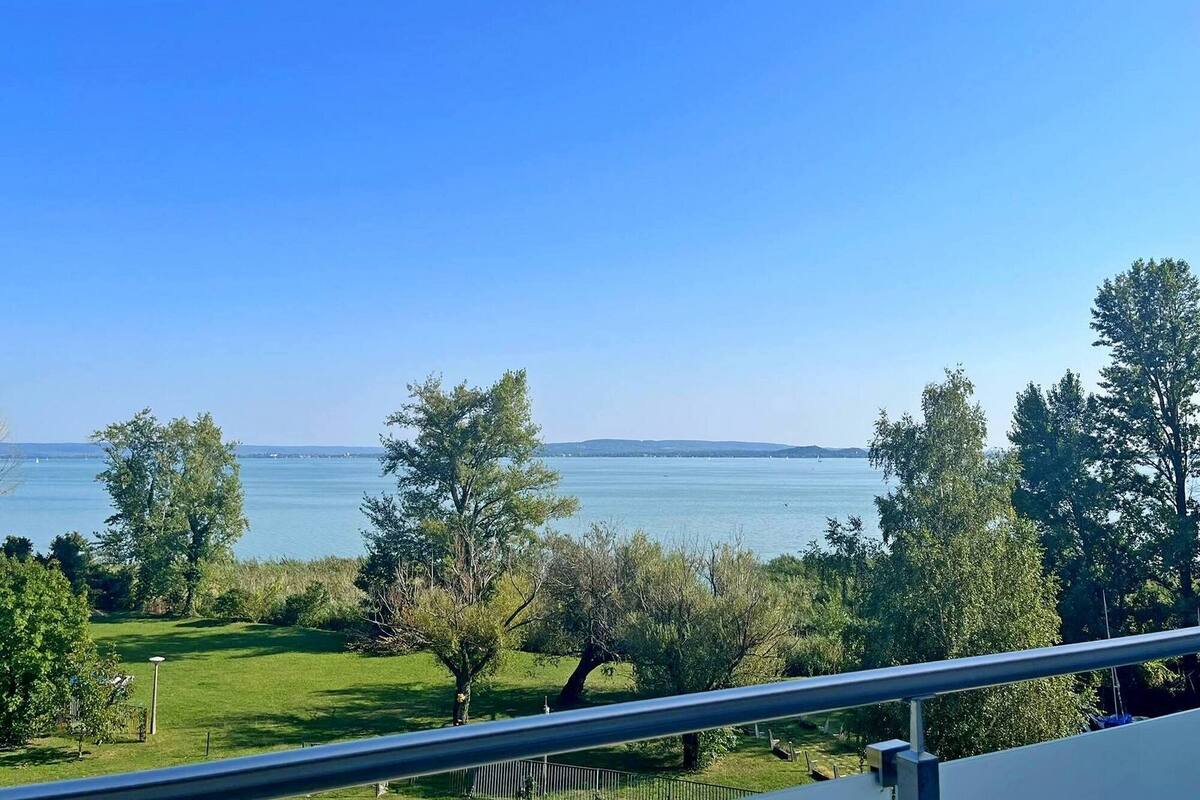 A balcony with a clear view of a lake and distant hills.